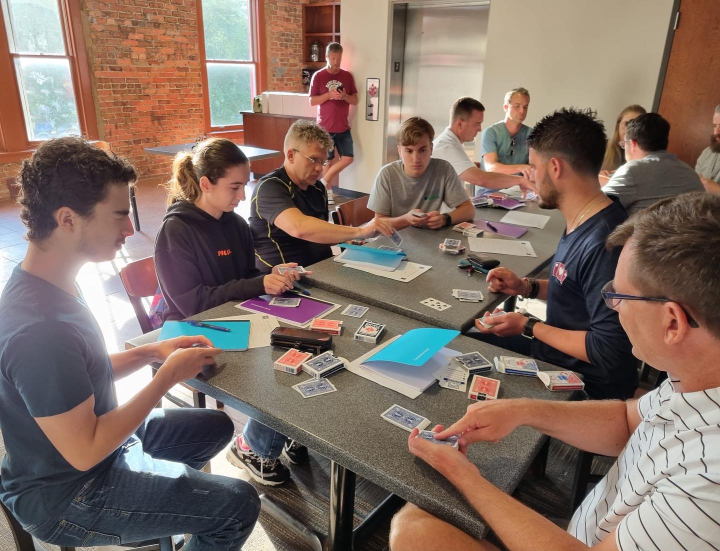 Milan leading a hands-on magic workshop with students practicing card tricks